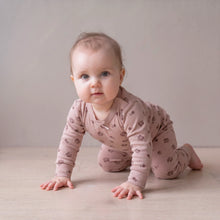 Load image into Gallery viewer, A baby crawling on a light wooden floor against a neutral beige wall, wearing a dusty pink long-sleeve one-piece pajama with a small brown floral pattern.