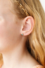 Load image into Gallery viewer, Close-up of a child wearing a blue ombré stud earring with three clustered gems in a gold-tone setting.