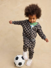 Load image into Gallery viewer, A toddler boy wearing a gray and black checkered zip-up hoodie and matching pants, standing on a soccer ball against a beige background.