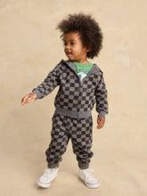 Load image into Gallery viewer, A toddler with curly dark hair stands against a warm beige studio backdrop wearing a gray and black checkerboard zip-up hoodie and matching jogger pants, with a green graphic shirt and white sneakers visible underneath.