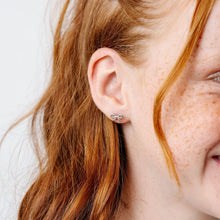 Load image into Gallery viewer, Close-up of a child wearing a silver-tone bow stud earring.