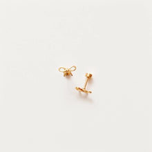 Load image into Gallery viewer, Pair of gold-tone bow stud earrings on a white background, showing the open-loop bow design and flat-back post.