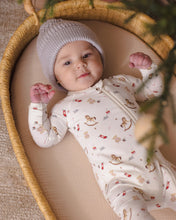 Load image into Gallery viewer, Baby lying in a woven basket wearing a cream Toy Chest print footie and a gray knit hat.