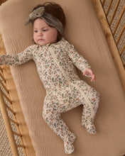 Load image into Gallery viewer, Baby lying in a wooden crib wearing a cream Holiday Floral footie with enclosed feet and a green bow headband.
