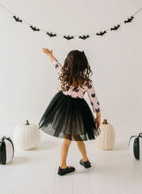 Load image into Gallery viewer, Child in a Halloween-themed outfit with black tulle skirt and pink top with black cat patterns, standing in front of white pumpkins and bat decorations.