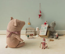 Load image into Gallery viewer, A styled collection of soft fabric toys and miniature dollhouse accessories arranged on a light wood floor against a pale green wall. The set includes a large pinkish-brown pig plush wearing a red gingham bow, a gray mouse, a small red-and-white doll, a miniature lamp, a tiny table with a green tea set, and a hanging red elf ornament.