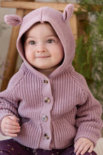 Load image into Gallery viewer, A close-up of a baby wearing a dusty pink hand-knit hooded cardigan with animal ears on the hood and brown buttons, set against a soft, blurred indoor background.