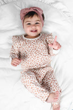 Load image into Gallery viewer, Baby in a leopard print outfit with a pink headband lying on a white blanket.