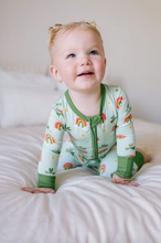 Load image into Gallery viewer, Baby wearing a green onesie with rainbow patterns sitting on a white surface.