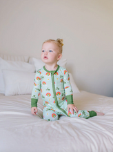 Load image into Gallery viewer, Baby wearing a green onesie with rainbow patterns on a bed.