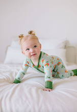 Load image into Gallery viewer, Baby in a green onesie with rainbow pattern on a white bed