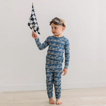 Load image into Gallery viewer, Child wearing a blue pajama set with car pattern, holding a checkered flag against a white background