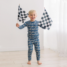 Load image into Gallery viewer, Child wearing a blue pajama set with car pattern, holding checkered flags against a white background