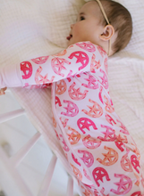 Load image into Gallery viewer, Baby wearing a pink and orange patterned onesie on a white blanket.