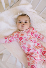 Load image into Gallery viewer, Baby lying on a white blanket wearing a pink outfit with horseshoe patterns.