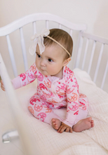 Load image into Gallery viewer, Baby in a pink and orange outfit sitting in a crib.