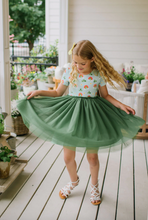 Load image into Gallery viewer, Young girl in a floral top and green skirt standing on a wooden deck.