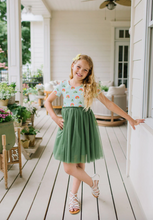 Load image into Gallery viewer, Young girl in a green dress standing on a wooden porch.