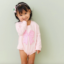 Load image into Gallery viewer, Child wearing a pink outfit with a large bow on a light green background