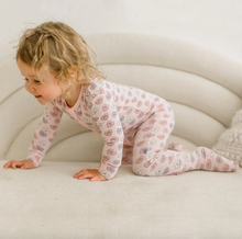 Load image into Gallery viewer, Child in a pink patterned onesie crawling on a white couch.