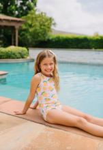 Load image into Gallery viewer, Young girl in a swimsuit sitting by a pool with greenery in the background