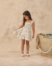 Load image into Gallery viewer, Young girl in a floral dress standing on a beige background