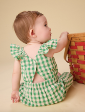 Load image into Gallery viewer, Baby in a green checkered outfit standing next to a woven basket on a beige background