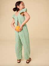 Load image into Gallery viewer, Child wearing a green checkered outfit holding an orange against a beige background