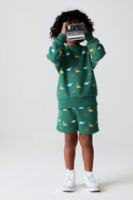 Load image into Gallery viewer, Child wearing a green outfit with animal patterns on a white background