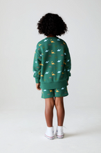 Load image into Gallery viewer, Child wearing a green outfit with animal patterns on a white background