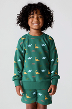 Load image into Gallery viewer, Child wearing a green outfit with dinosaur patterns on a plain background