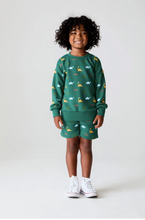 Load image into Gallery viewer, Child wearing a green outfit with animal patterns on a white background