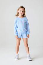 Load image into Gallery viewer, Young girl wearing a light blue sweatshirt and shorts set with colorful designs on a white background