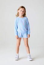 Load image into Gallery viewer, Young girl wearing a light blue sweatshirt and shorts set with colorful designs on a white background