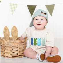 Load image into Gallery viewer, Baby wearing a shirt with colorful bunny designs, sitting next to a basket with bunny ears.