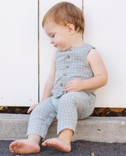 Load image into Gallery viewer, Child wearing a light blue checkered outfit sitting on a step.