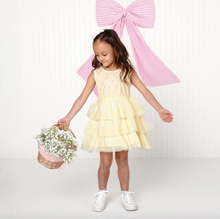 Load image into Gallery viewer, Young girl in a yellow dress holding flowers with a large pink bow in the background