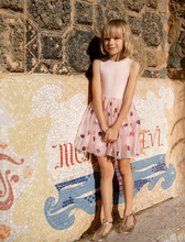 Load image into Gallery viewer, Young girl in a pink dress standing in front of a mosaic wall with decorative text.