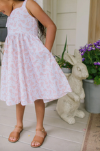 Load image into Gallery viewer, Person wearing a light pink floral dress standing on a porch with decorative elements.