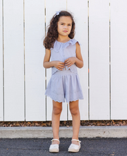 Load image into Gallery viewer, Young girl in a light blue dress standing against a white wooden fence.