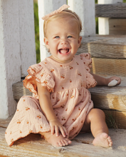 Load image into Gallery viewer, Smiling baby in a pink dress with ruffled sleeves sitting on wooden steps.