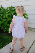 Load image into Gallery viewer, Child wearing a pink floral romper standing on a sidewalk with greenery in the background