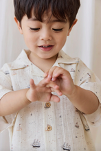 Load image into Gallery viewer, Child wearing a patterned shirt with a neutral background
