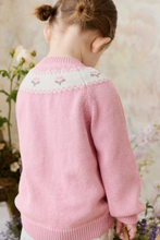 Load image into Gallery viewer, Child wearing a pink knitted cardigan with floral patterns in a garden setting