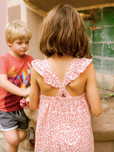 Load image into Gallery viewer, Child wearing a red floral dress with cut-out back design, standing outdoors.