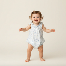 Load image into Gallery viewer, Baby in a light blue romper with white polka dots on a beige background