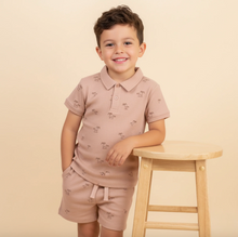 Load image into Gallery viewer, Child wearing a pink polo shirt and shorts set on a beige background