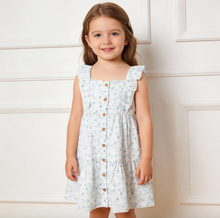 Load image into Gallery viewer, Young girl wearing a light blue floral dress with brown buttons against a white wall.