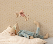 Load image into Gallery viewer, Child's stuffed toy in pajamas lying on a bed with another toy hanging above.