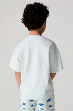 Load image into Gallery viewer, Child wearing a light blue t-shirt and white pants with blue shark patterns on a plain background